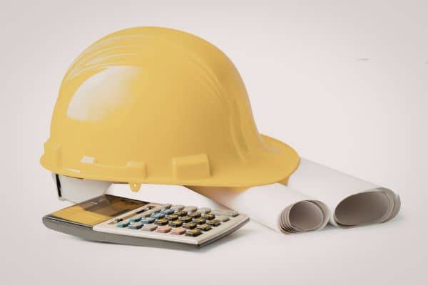  Calculator with rolled blueprints and construction hard hat representing land survey cost estimation and project budgeting